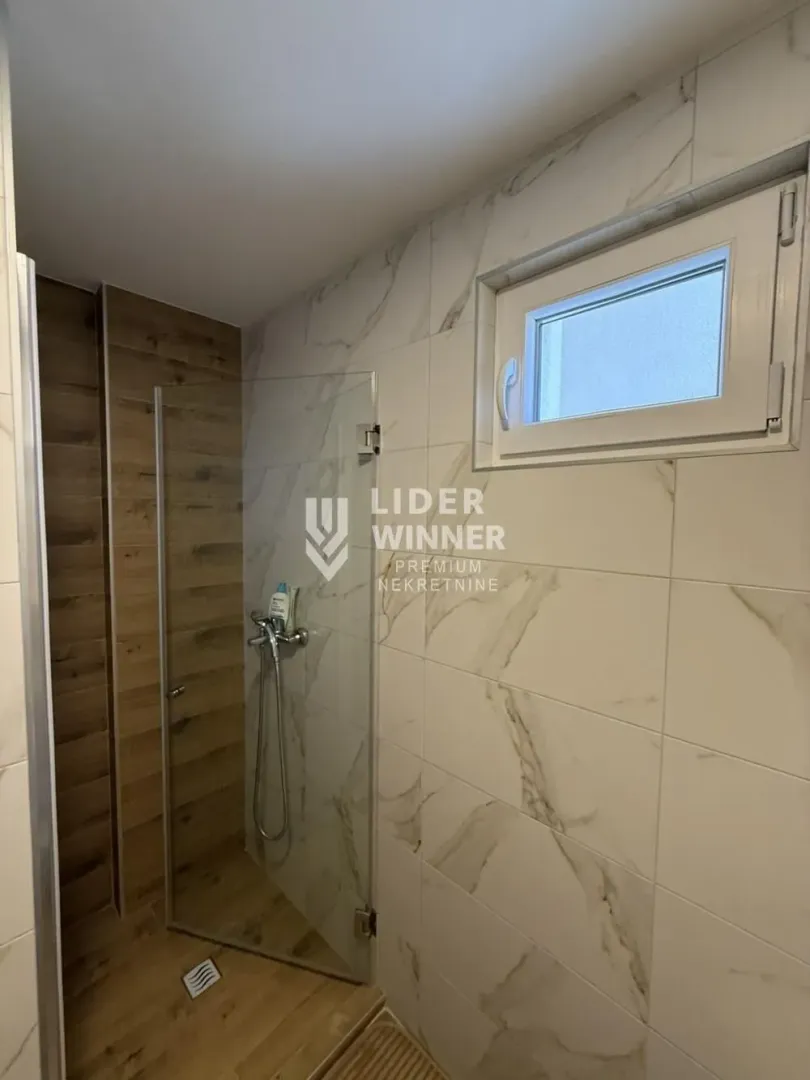Moderno opremljeno kupatilo sa tuš kabinom.