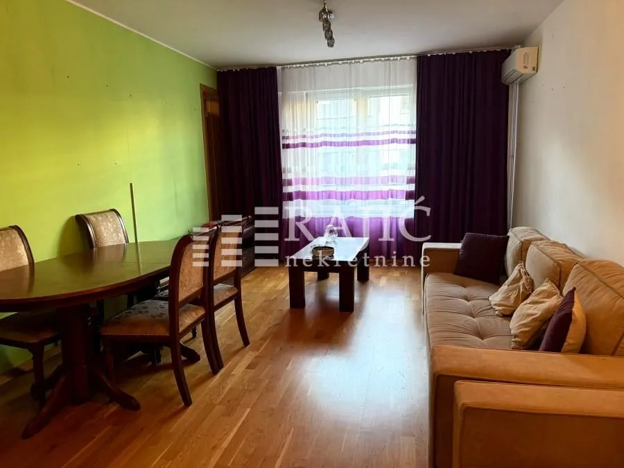 Living room with a sofa, dining table, and green wall.