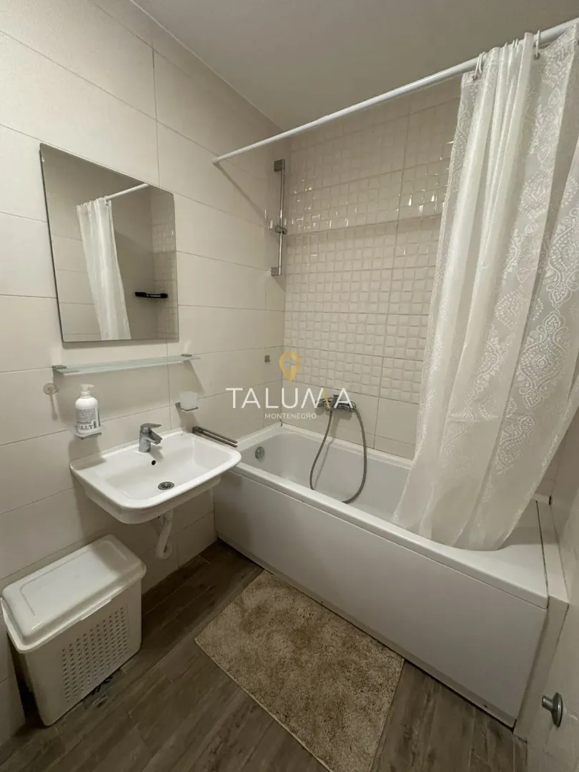 Bathroom equipped with a bathtub, washbasin, mirror, and a white shower curtain.