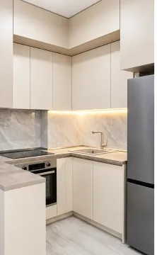 Modern kitchen with light cabinetry, built-in oven, and refrigerator. - image 2