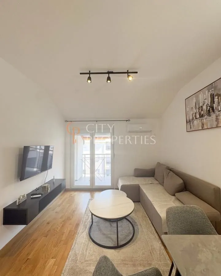 Living room with a sectional sofa, TV, and balcony access.