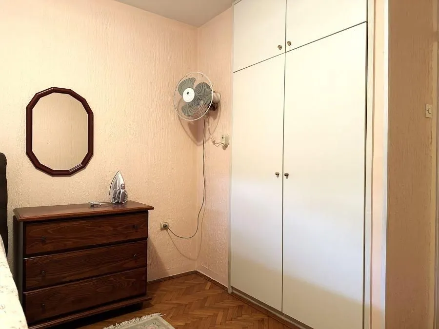Small bedroom with a wooden dresser and built-in wardrobe.