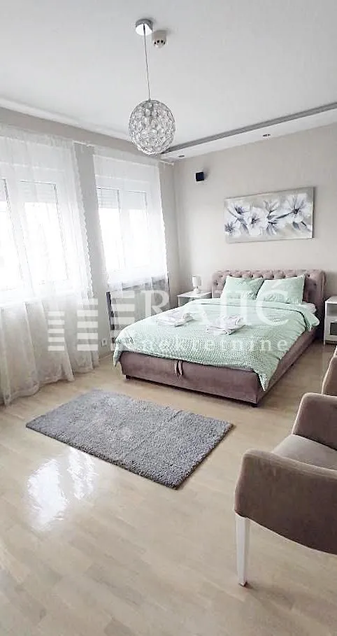 Tidy bedroom with a double bed, windows, and modern lighting.