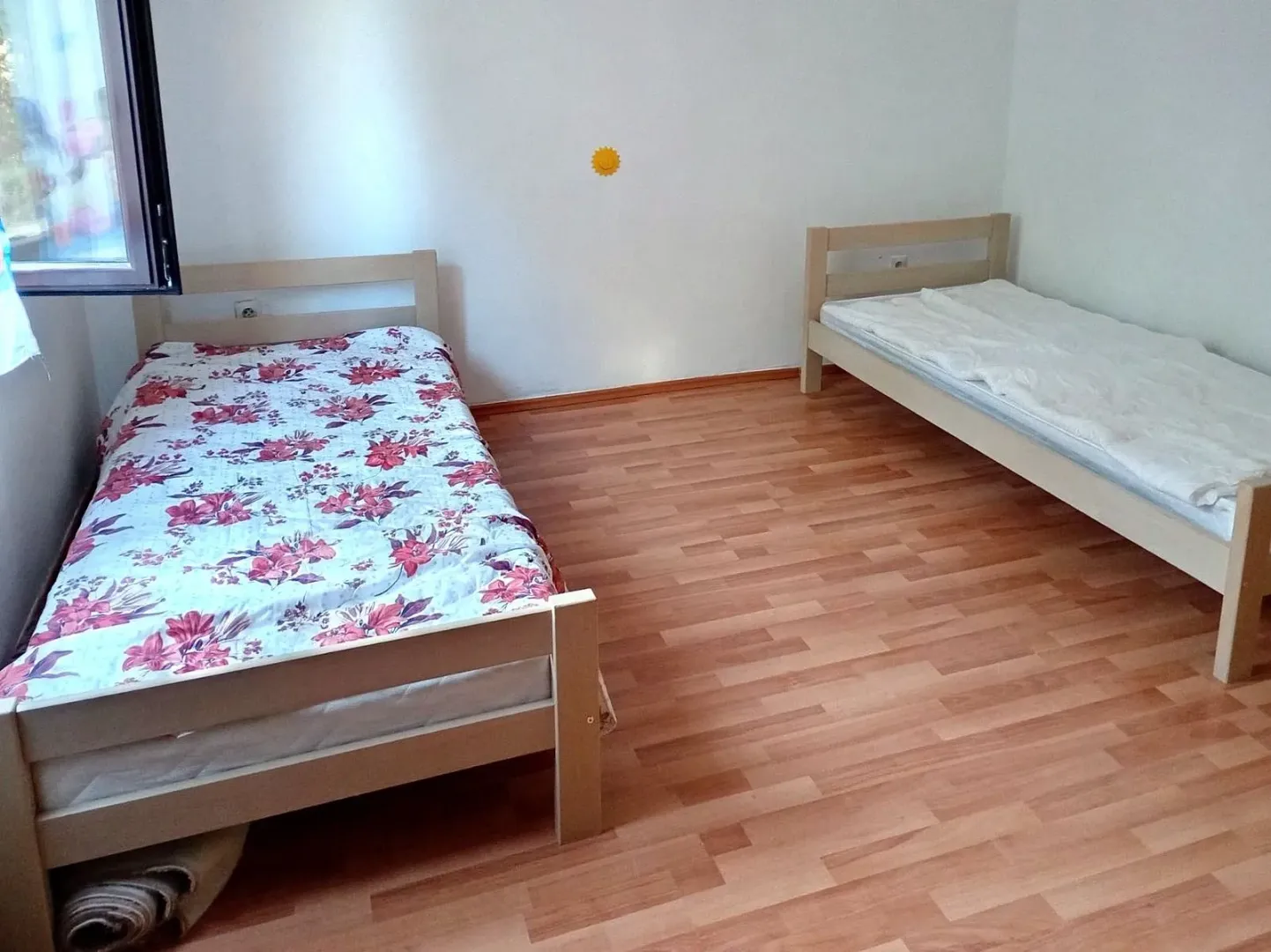 Bedroom with two wooden beds and laminate flooring.