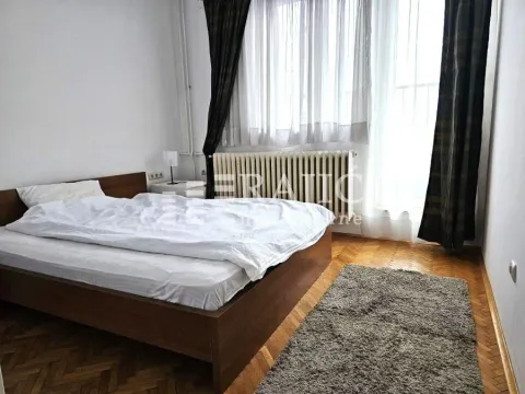 Spavaća soba sa bračnim krevetom, parketom i prozorom sa zavesama. - image 10