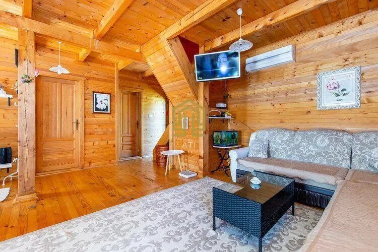 Living room in a wooden cottage with a sofa and staircase.