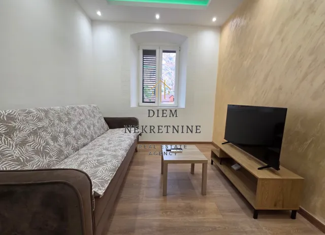 Dnevna soba sa garniturom, stočićem i televizorom.