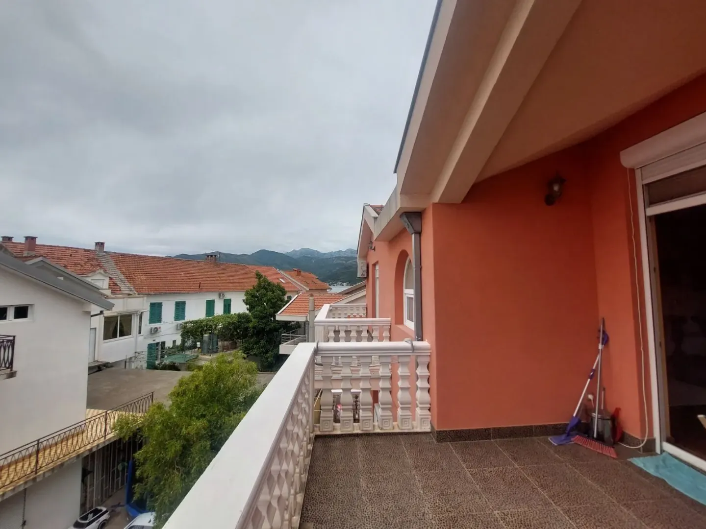 Prostrana terasa sa pogledom na okolne zgrade i planine.