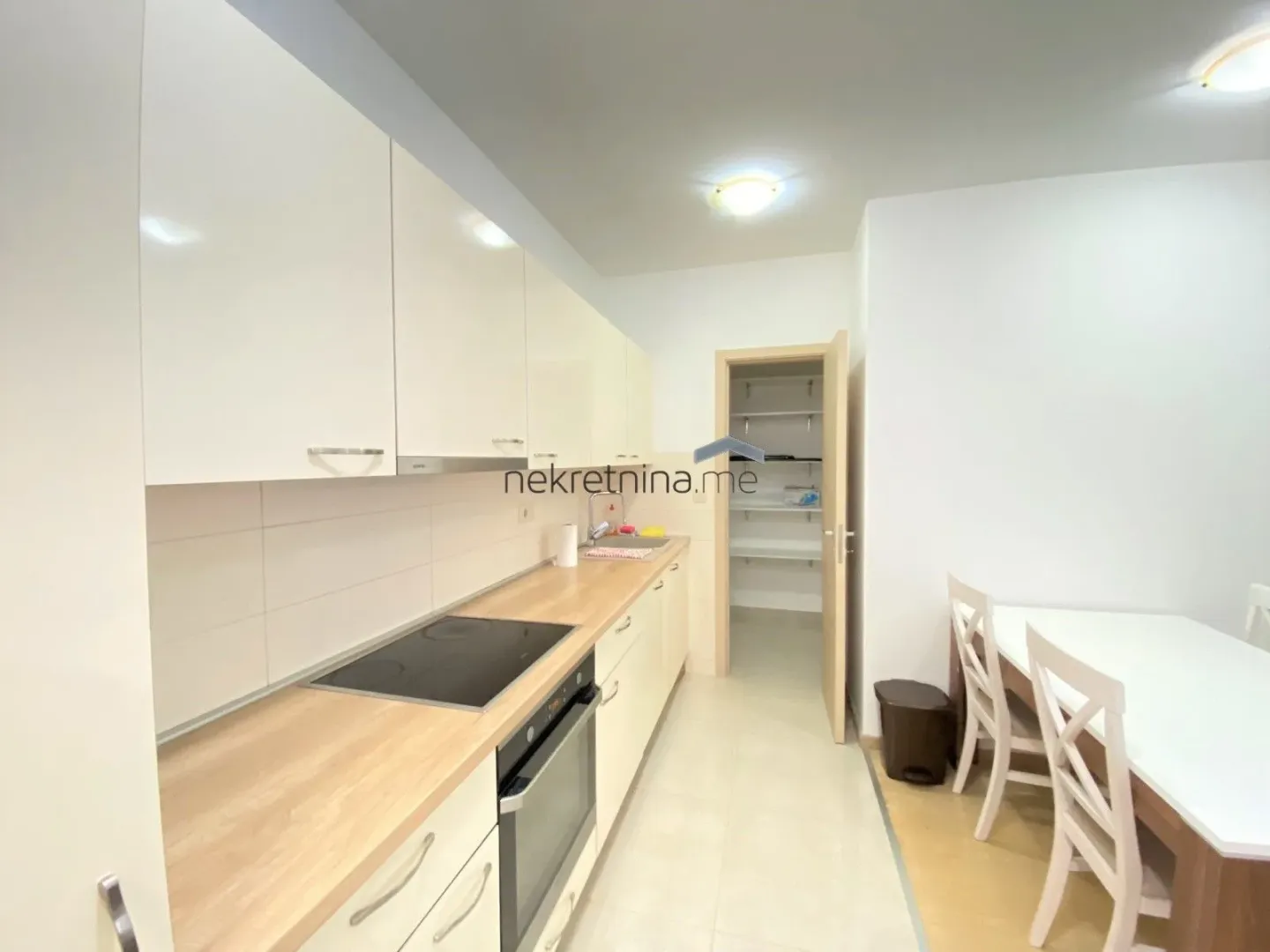 Modern kitchen with white cabinets and a wooden countertop.