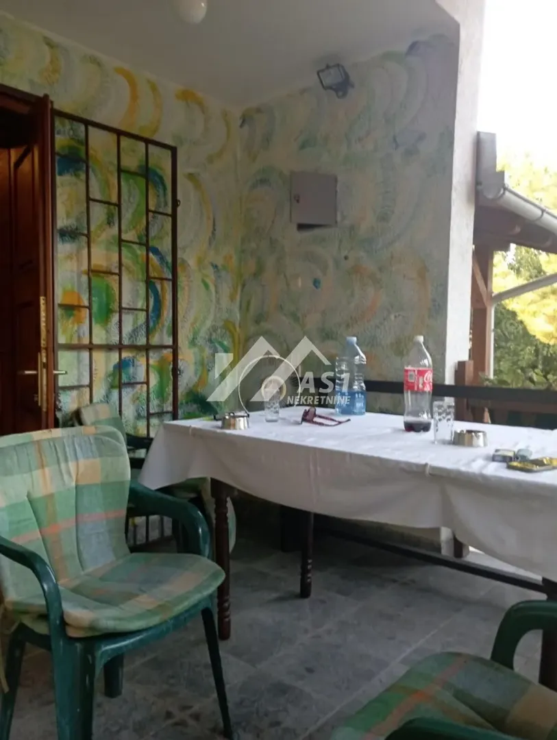 Natkrivena terasa sa stolom, stolicama i oslikanim zidom.