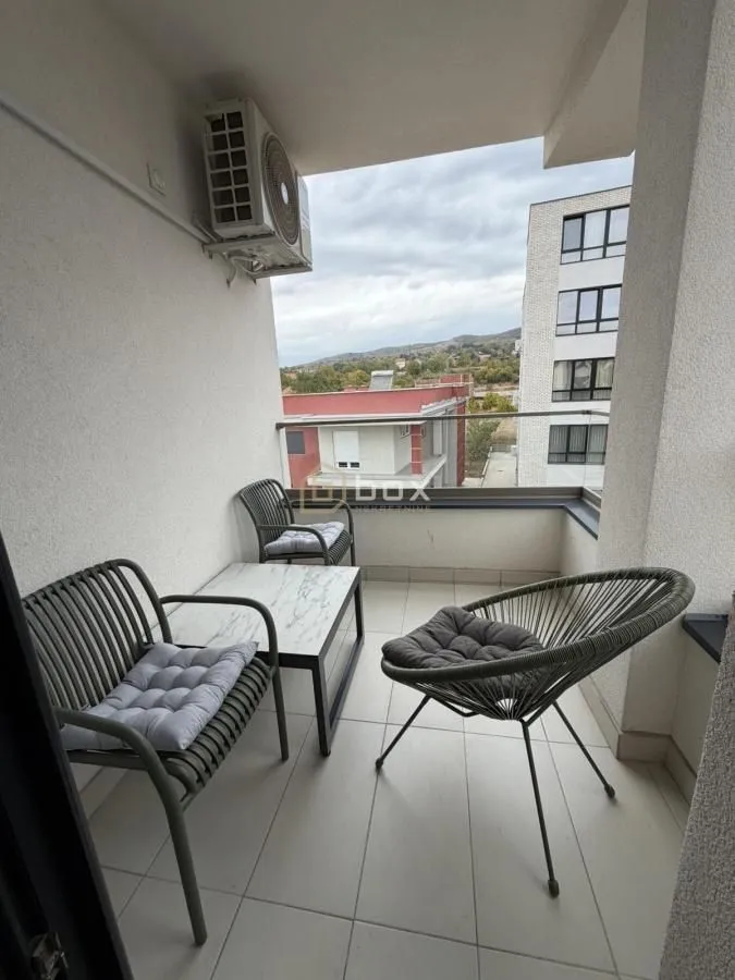 Namešten balkon sa garniturom za sedenje i pogledom na okolinu.
