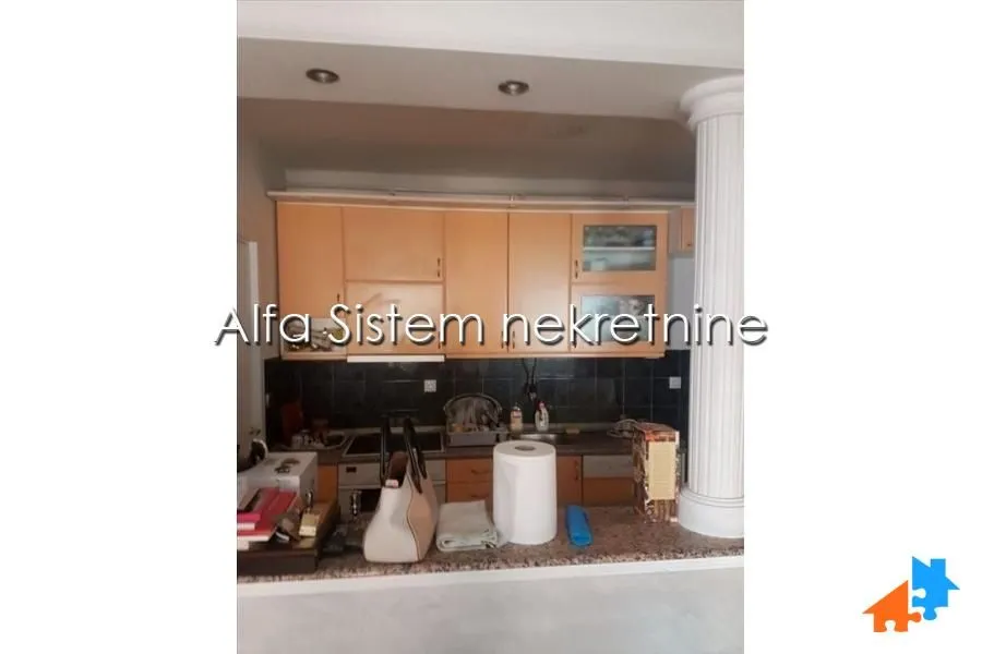 Manja kuhinja sa drvenim elementima i šankom.