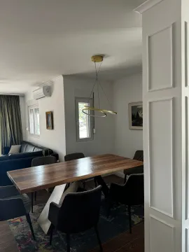 Trpezarija sa velikim drvenim stolom i modernim lusterom. - image 19