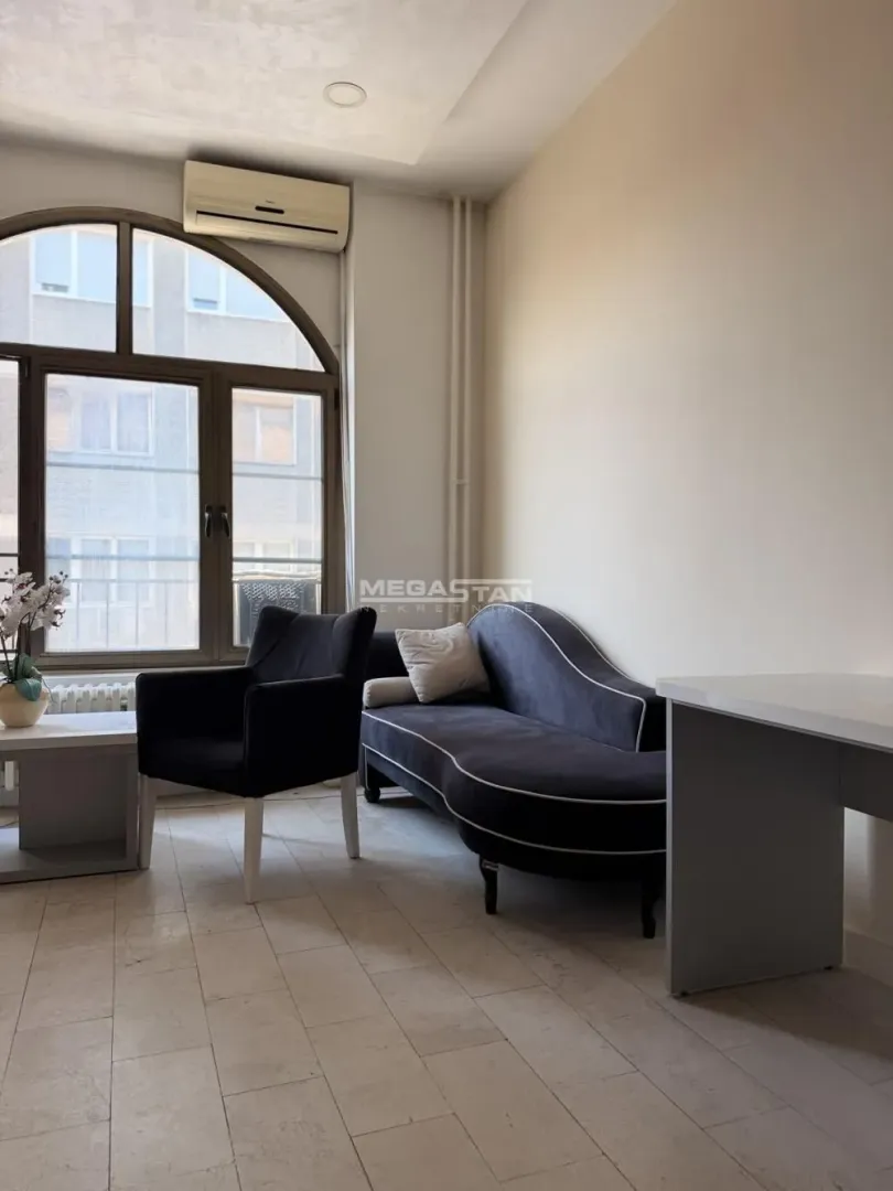Living room with furniture and a large arched window.