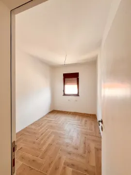 Prazna soba sa drvenim podom i prozorom gledana kroz otvoren vrata. - image 7