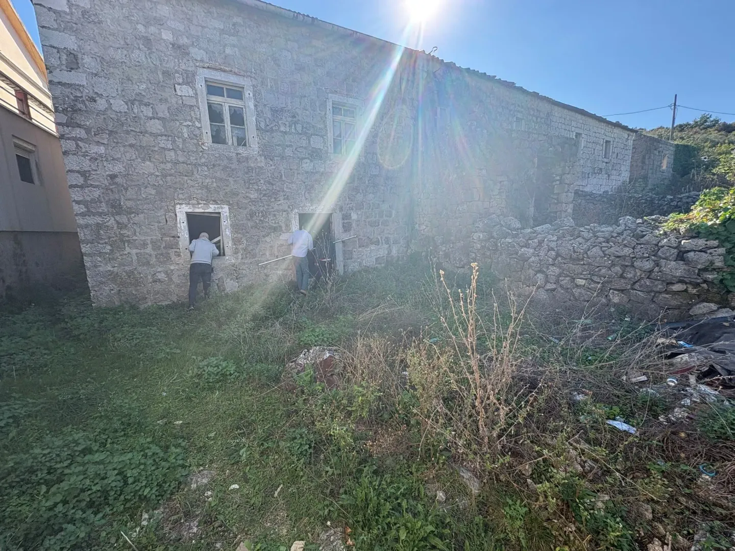 Eksterijer stare kamene kuće sa dvorištem.