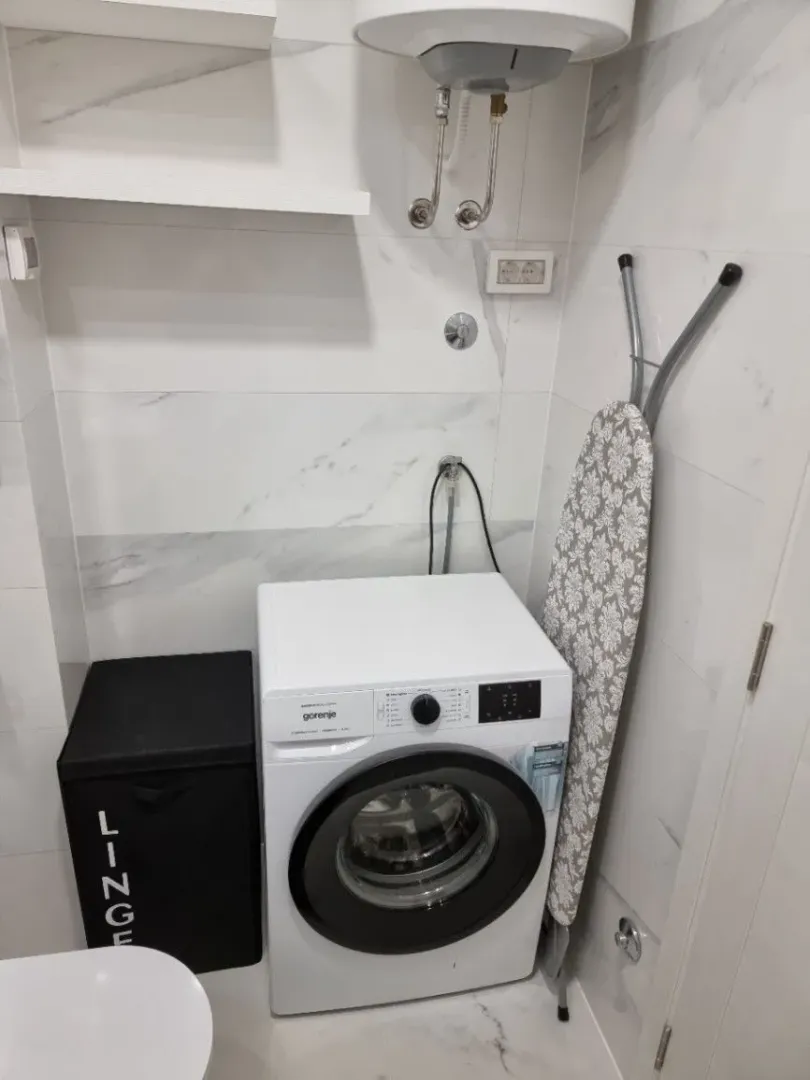 Washing machine and water heater in a brightly tiled bathroom.