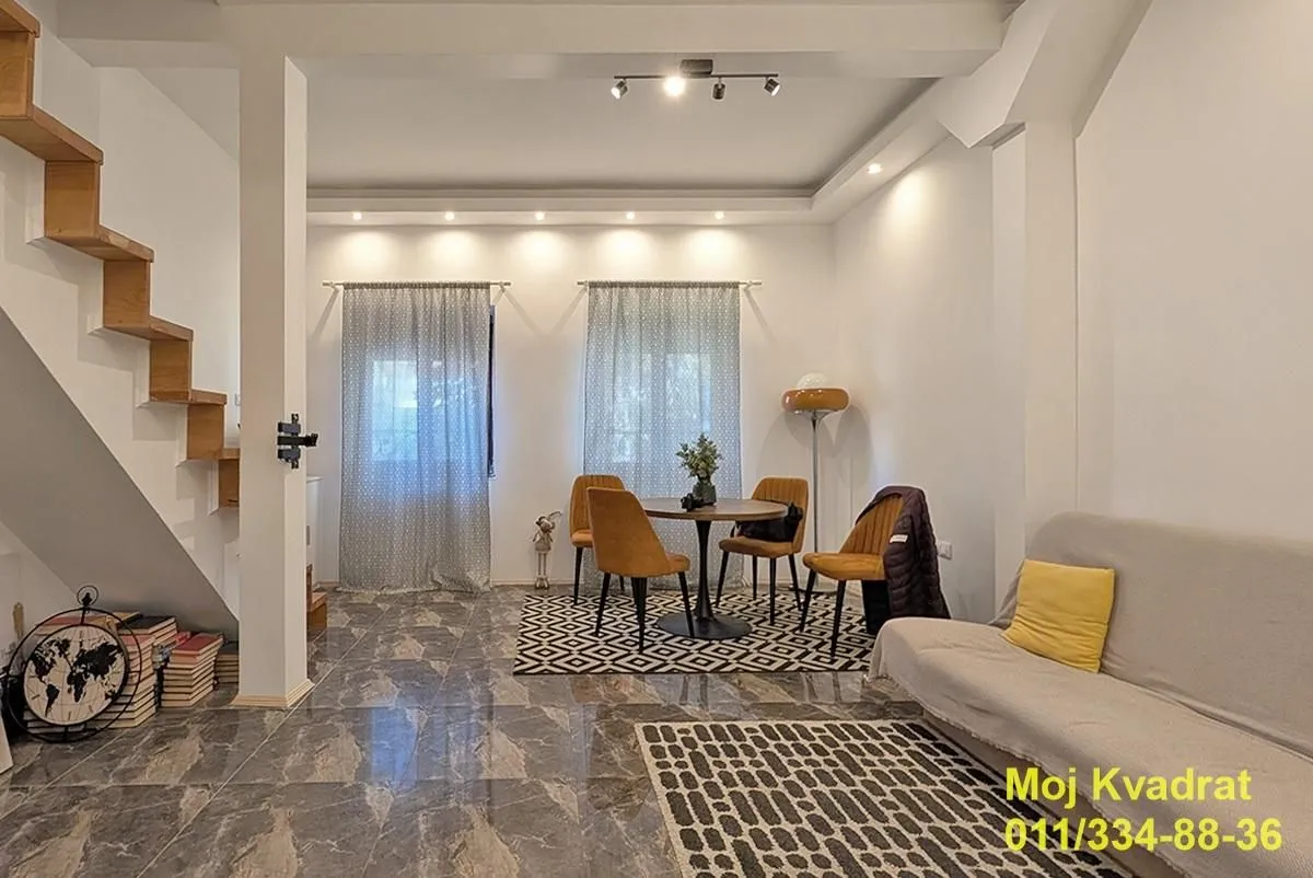 Living room with a sofa, dining table, and interior staircase.