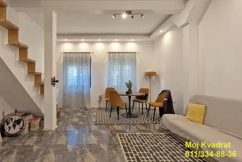 Living room with a sofa, dining table, and interior staircase. - image 17