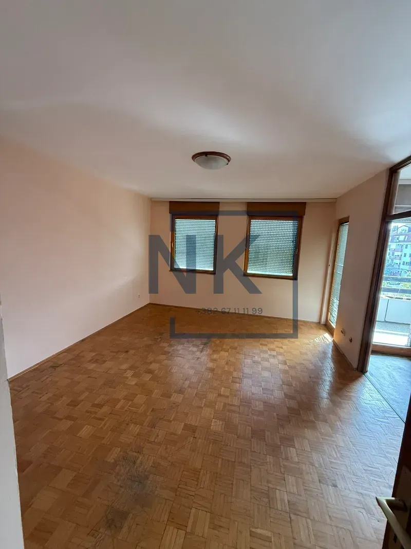 Empty room with hardwood floors and windows.
