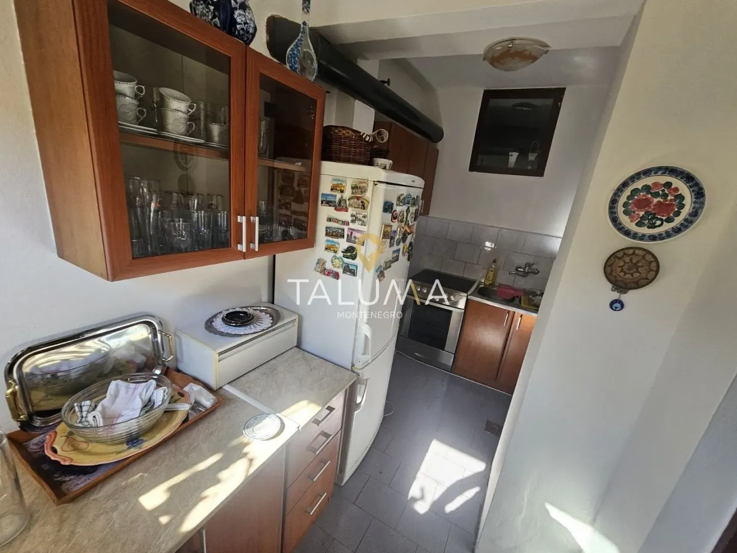Small kitchen with wooden cabinets, refrigerator, and stove.