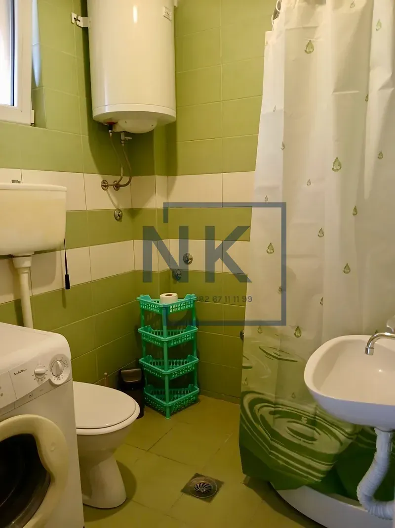 Bathroom with a shower cabin, toilet, washbasin, and water heater.