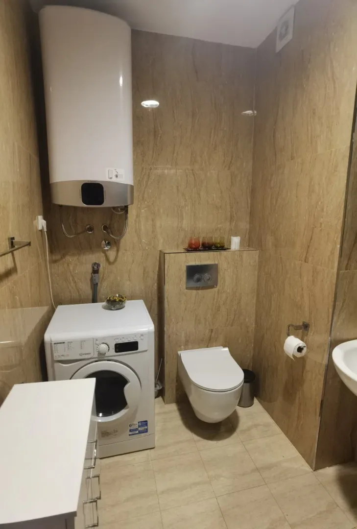 Modernly equipped bathroom with a washing machine and built-in elements.