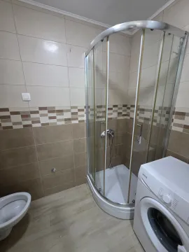 Small bathroom with a shower cabin, toilet, and washing machine. - image 5