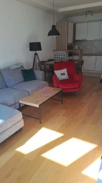 Living room with a sofa, armchair and dining area in the background. - image 2
