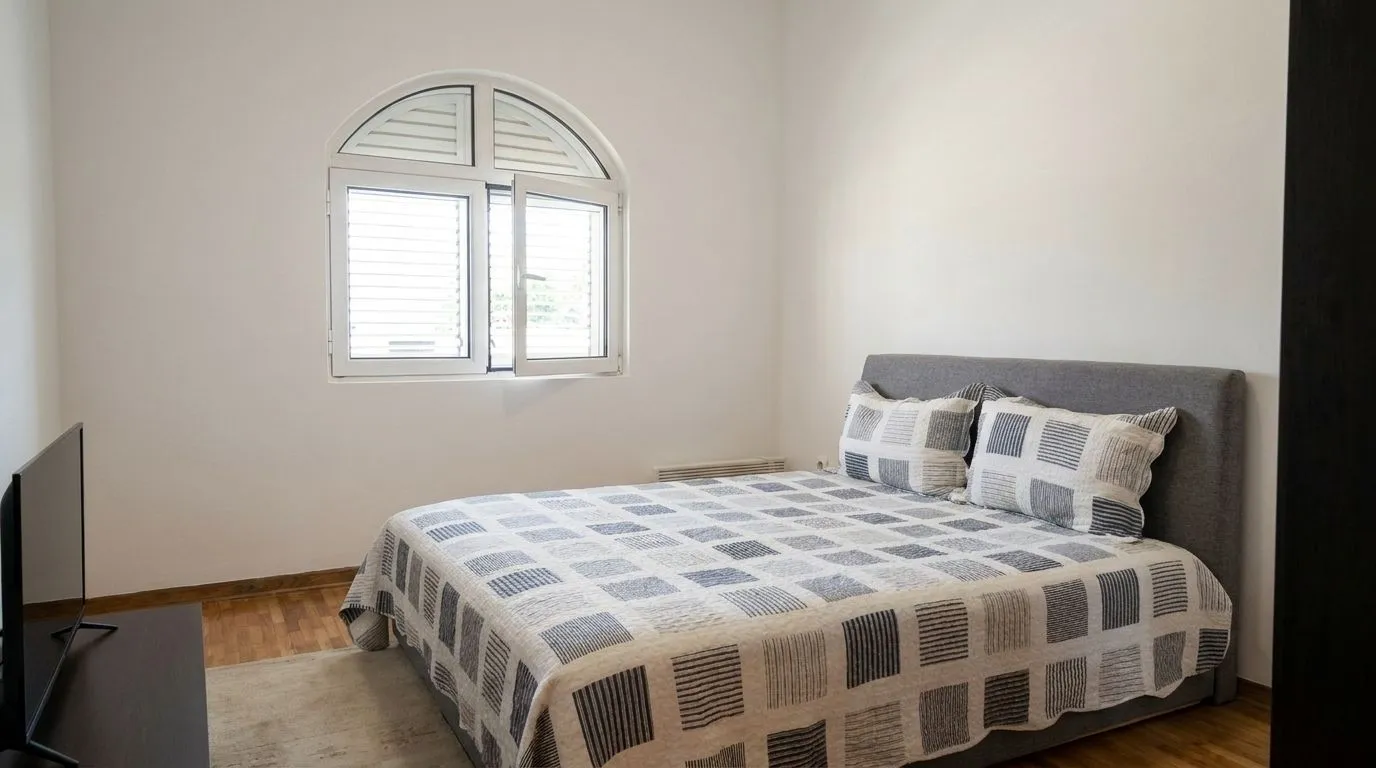Bright bedroom with a double bed and an arched window.