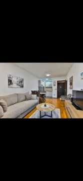 Living room with a sofa, coffee table and dining area in the background. - image 11
