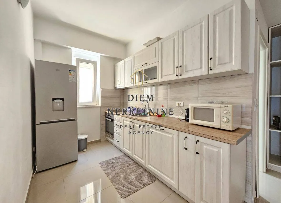 Small kitchen with white cabinets and a refrigerator.