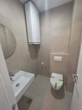 Modern bathroom equipped with a shower drain and water heater. - image 9