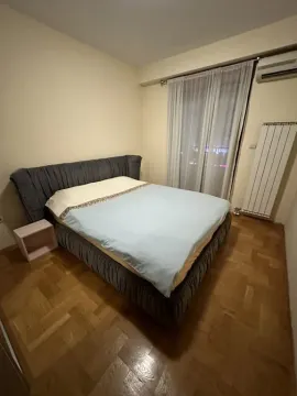 Spavaća soba sa bračnim krevetom, drvenim parketom i prozorom sa zavjesama. - image 6