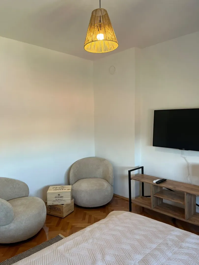 Comfortable bedroom with a bed, armchairs, and a wall-mounted TV.