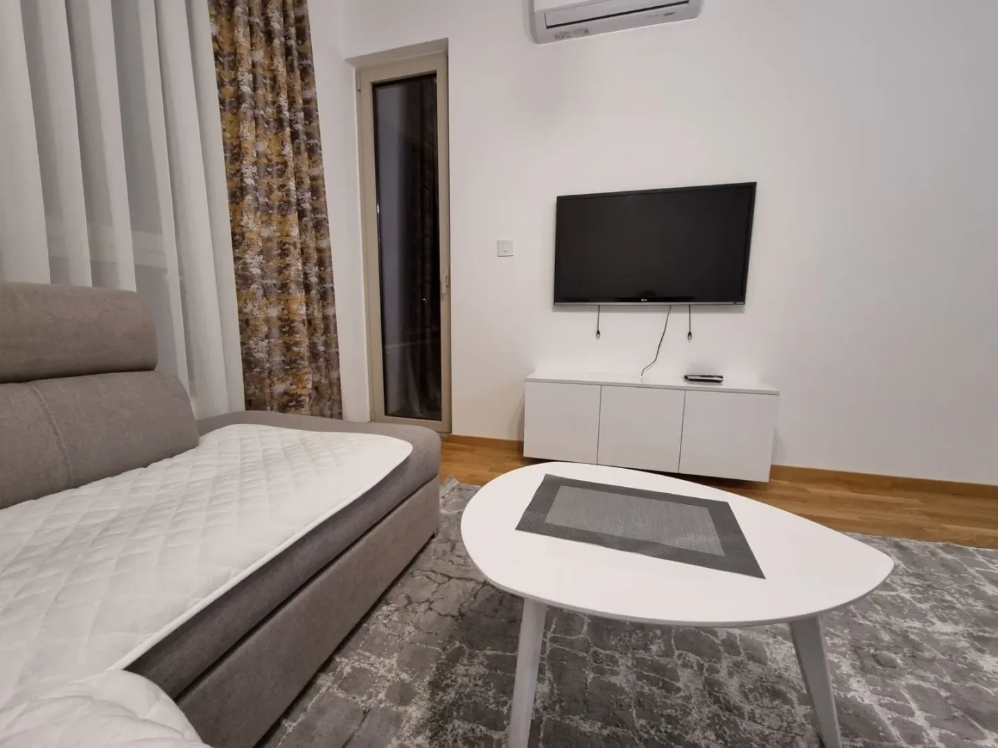 Living room with a sectional sofa, coffee table, and wall-mounted TV.