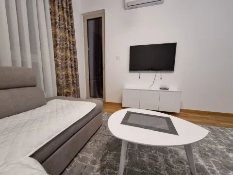 Living room with a sectional sofa, coffee table, and wall-mounted TV. - image 5