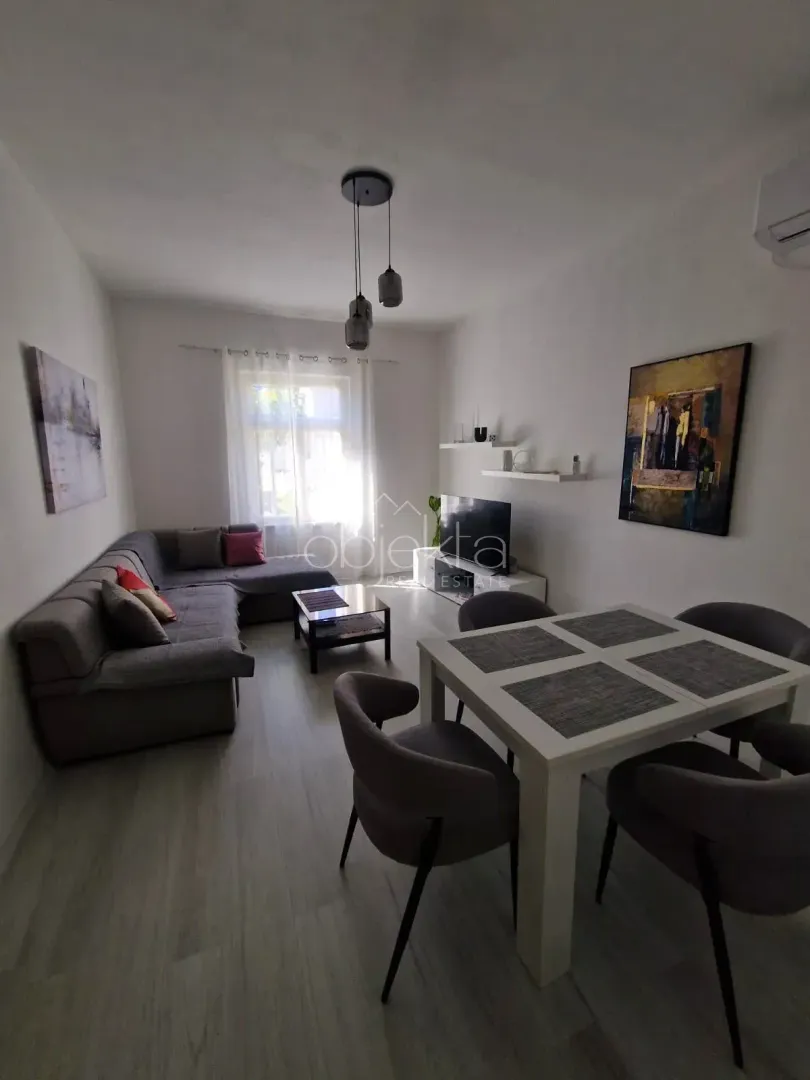 Living room with a sofa, TV, and dining table with chairs.