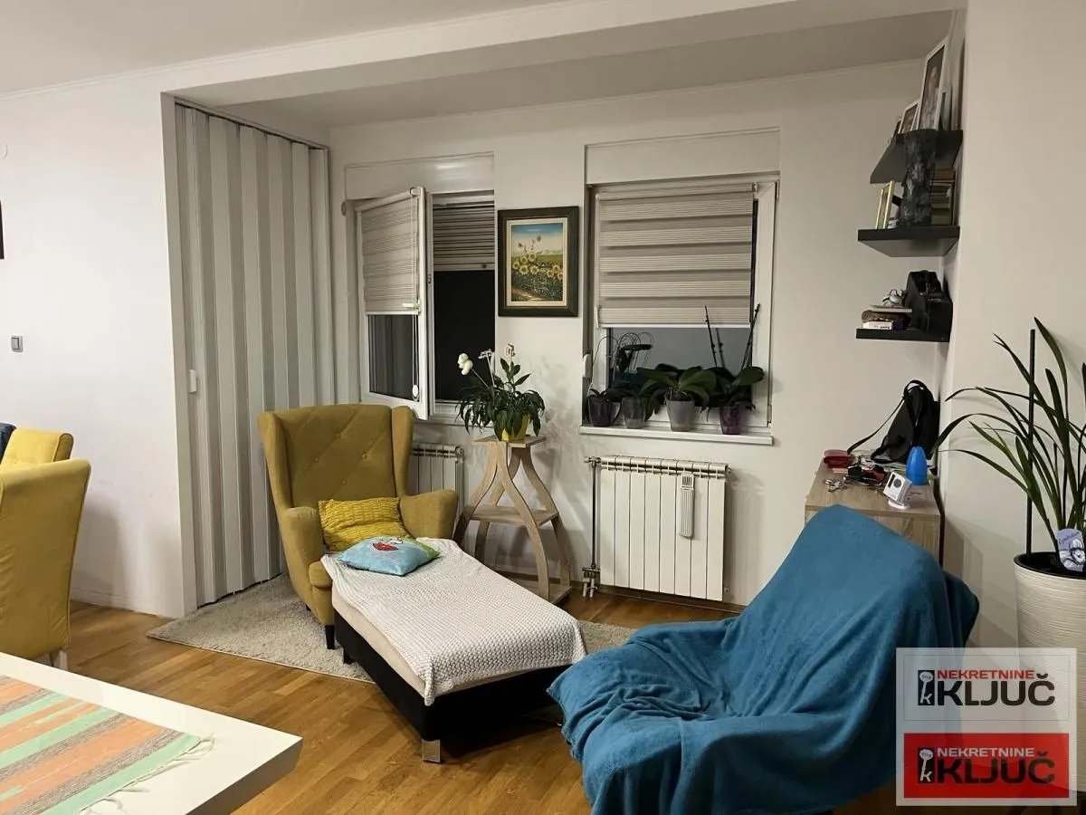 Dnevni boravak sa foteljom, kaučem i prozorima.