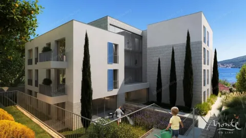 Pogled na spoljašnjost moderne stambene zgrade sa uređenim dvorištem i pogledom na more. - image 4