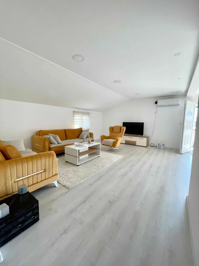 Spacious living room with a sofa set, armchair, and TV unit.