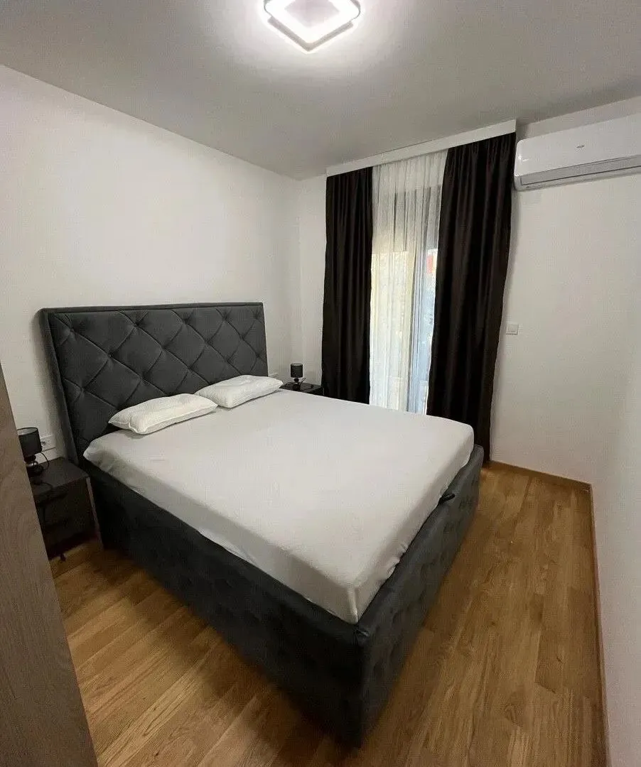 Furnished bedroom with a double bed, dark curtains, and an air conditioner.