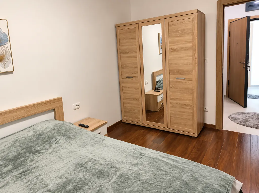 Namještena spavaća soba sa krevetom, ormarom i noćnim stočićem.