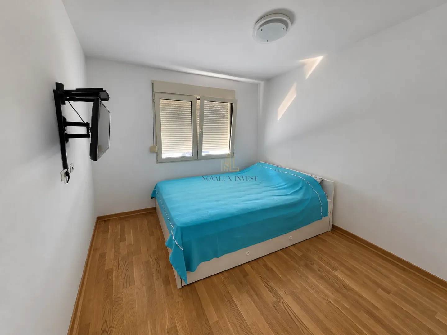 Small bedroom with a bed and a wall-mounted TV.