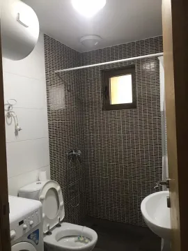 Bathroom with dark tiles, a toilet, and a washing machine. - image 5