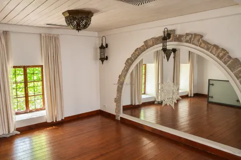 Empty room with wooden flooring, a white ceiling, and a large mirror framed by a stone arch. - image 3