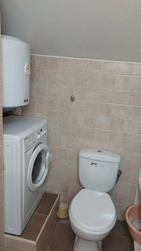 Smaller bathroom with a toilet, washing machine, and water heater.