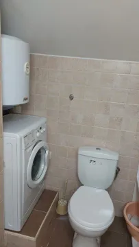 Smaller bathroom with a toilet, washing machine, and water heater. - image 6