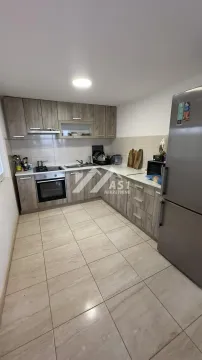 Kitchen equipped with wooden cabinetry and built-in home appliances. - image 4