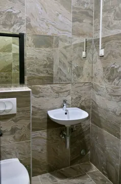 Small bathroom with a sink and ceramic tiles. - image 6
